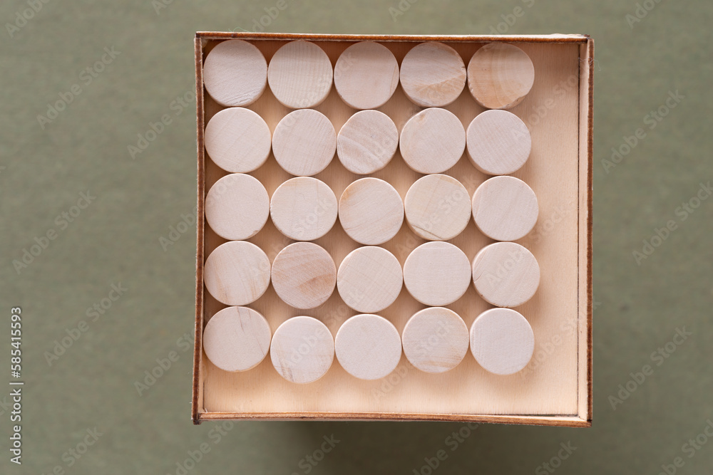 Fototapeta premium wood circles neatly organized inside a shallow wooden box (photographed on a green background)