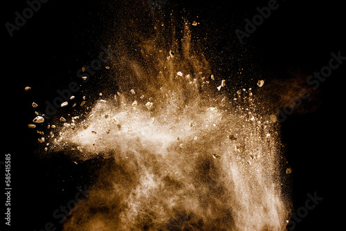 Split debris of stone exploding with brown powder against white background.