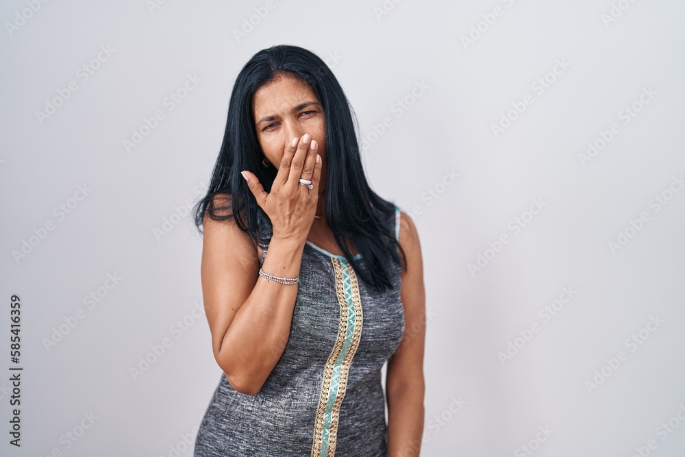 Mature hispanic woman standing over white background bored yawning tired covering mouth with hand. restless and sleepiness. Mature hispanic woman standing over white background bored yawning tired covering mouth with hand. restless and sleepiness.