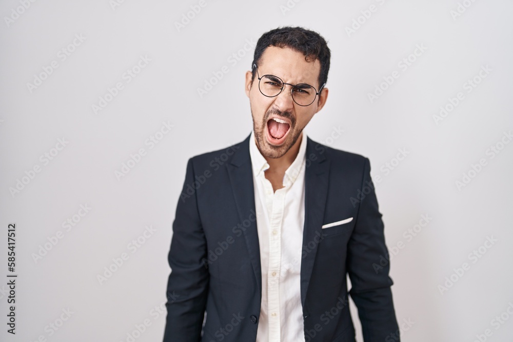 Handsome business hispanic man standing over white background angry and mad screaming frustrated and furious, shouting with anger. rage and aggressive concept. Handsome business hispanic man standing over white background angry and mad screaming frustrated and furious, shouting with anger. rage and aggressive concept.