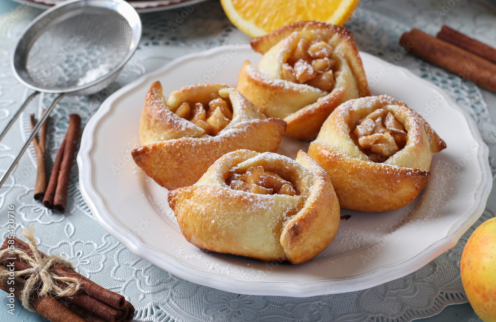 Buns with apples and cinnamon in the form of roses, sprinkled with powdered sugar Buns with apples and cinnamon in the form of roses, sprinkled with powdered sugar