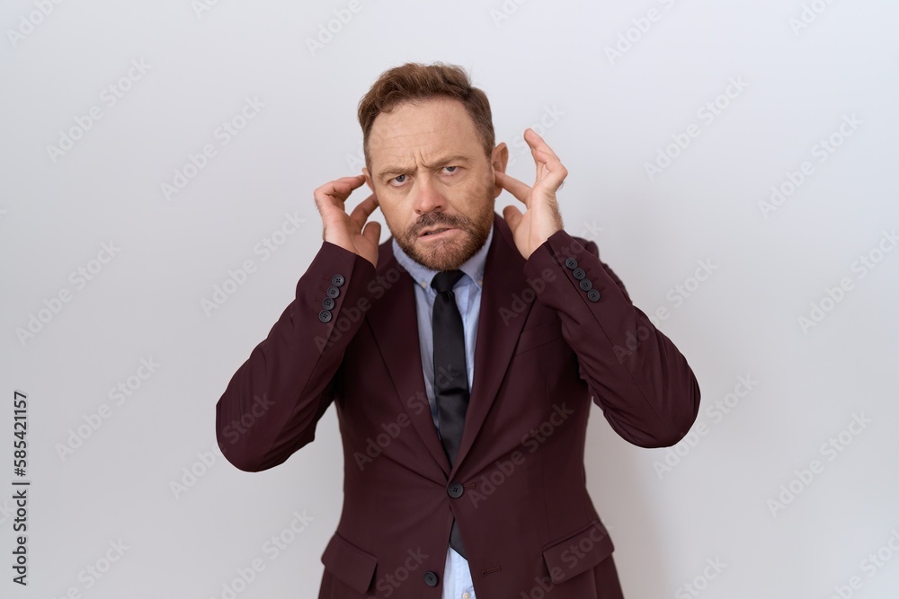 Middle age business man with beard wearing suit and tie covering ears with fingers with annoyed expression for the noise of loud music. deaf concept. Middle age business man with beard wearing suit and tie covering ears with fingers with annoyed expression for the noise of loud music. deaf concept.