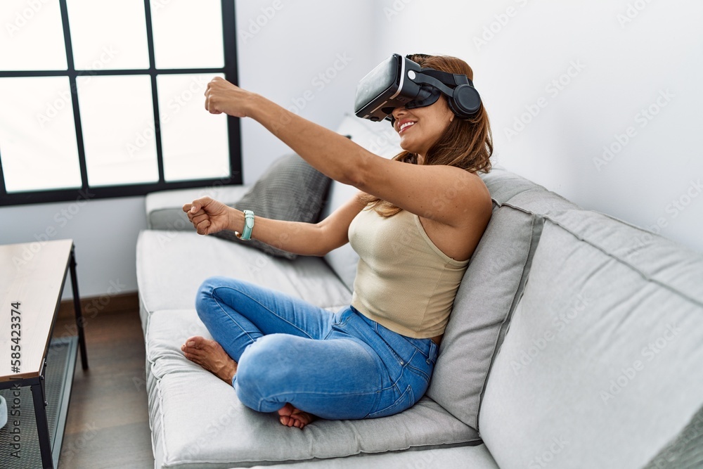 Young latin woman playing video game using virtual reality glasses at home Young latin woman playing video game using virtual reality glasses at home