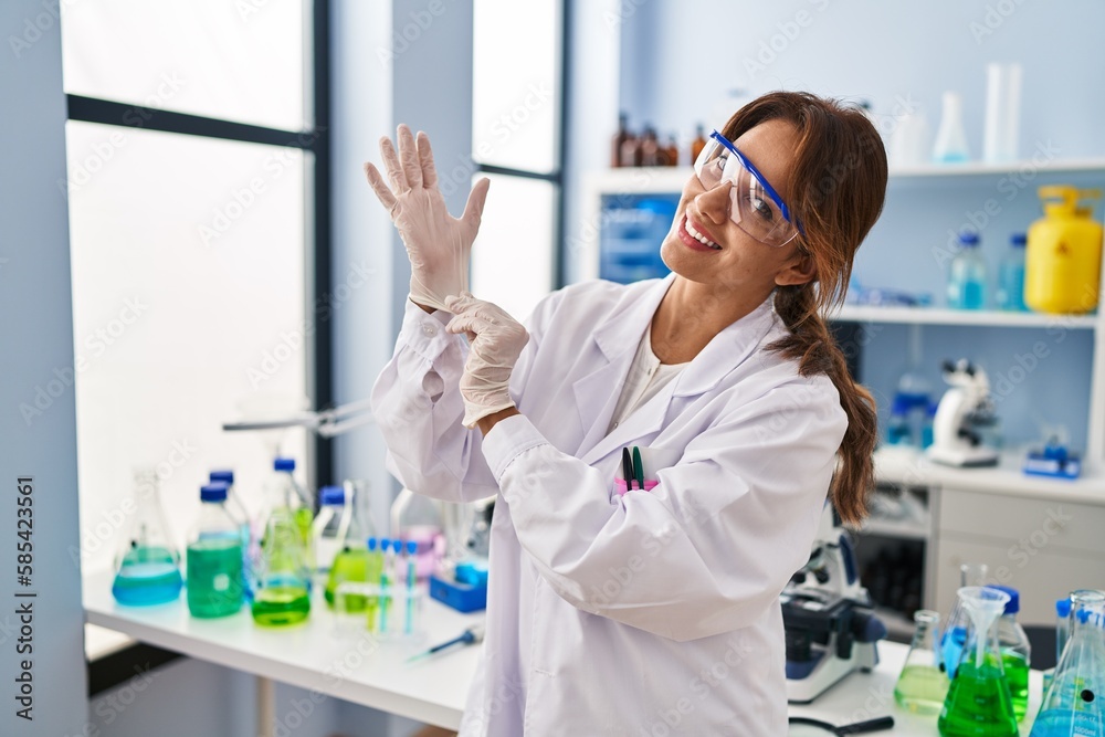 Young latin woman wearing scientist uniform and gloves at laboratory Young latin woman wearing scientist uniform and gloves at laboratory