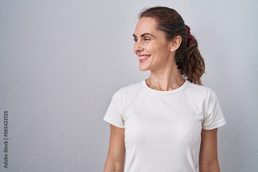 Beautiful brunette woman standing over isolated background looking away to side with smile on face, natural expression. laughing confident. Beautiful brunette woman standing over isolated background looking away to side with smile on face, natural expression. laughing confident.