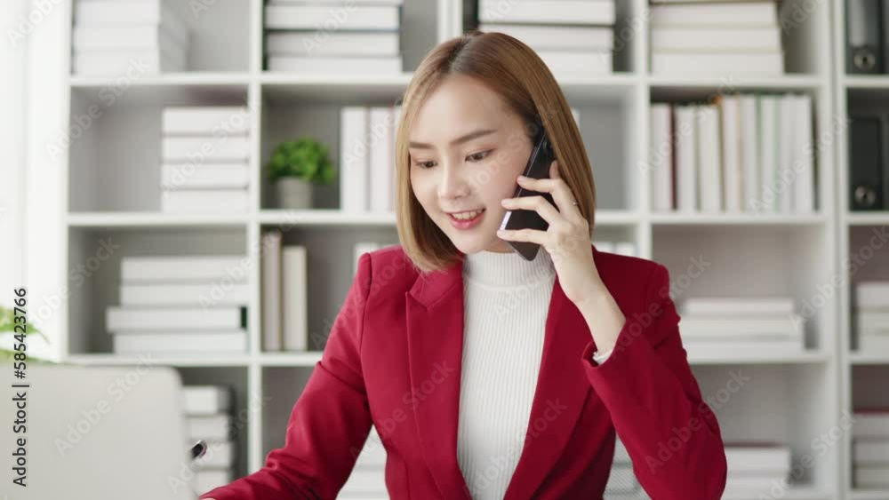 Young businesswomen in red suit working and talking with happy and smile face on a phone calling to client and colleague in office space. Young businesswomen in red suit working and talking with happy and smile face on a phone calling to client and colleague in office space.