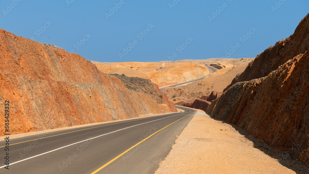 Winding road through barren desert mining country with dark blue sky