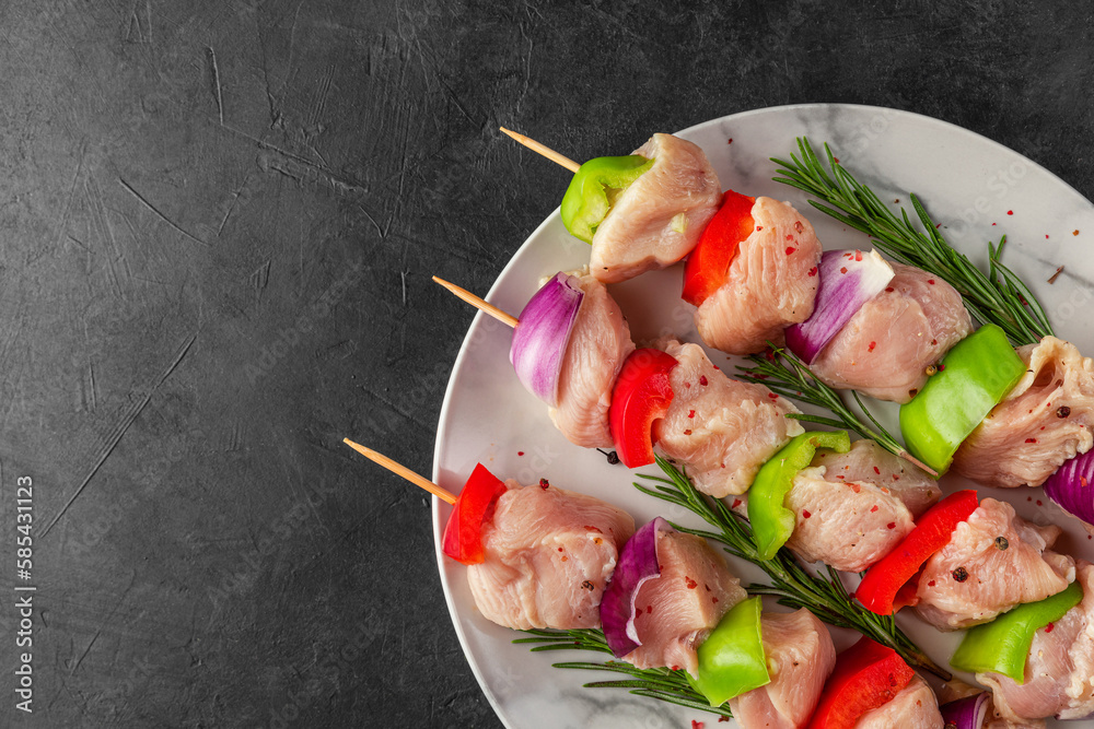 Raw chicken meat pieces with vegetables, pepper and onion on skewers for cooking chicken kebab or bbq. Top view