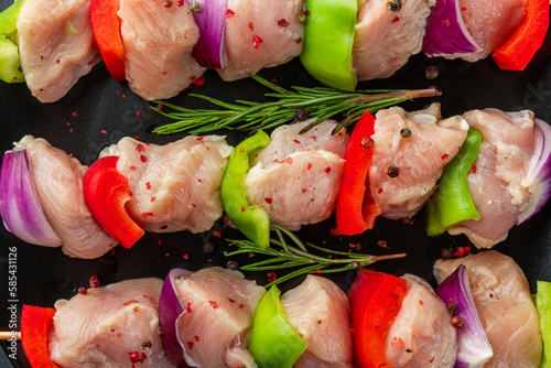 Raw chicken meat pieces with vegetables, pepper and onion on skewers for cooking chicken kebab or bbq