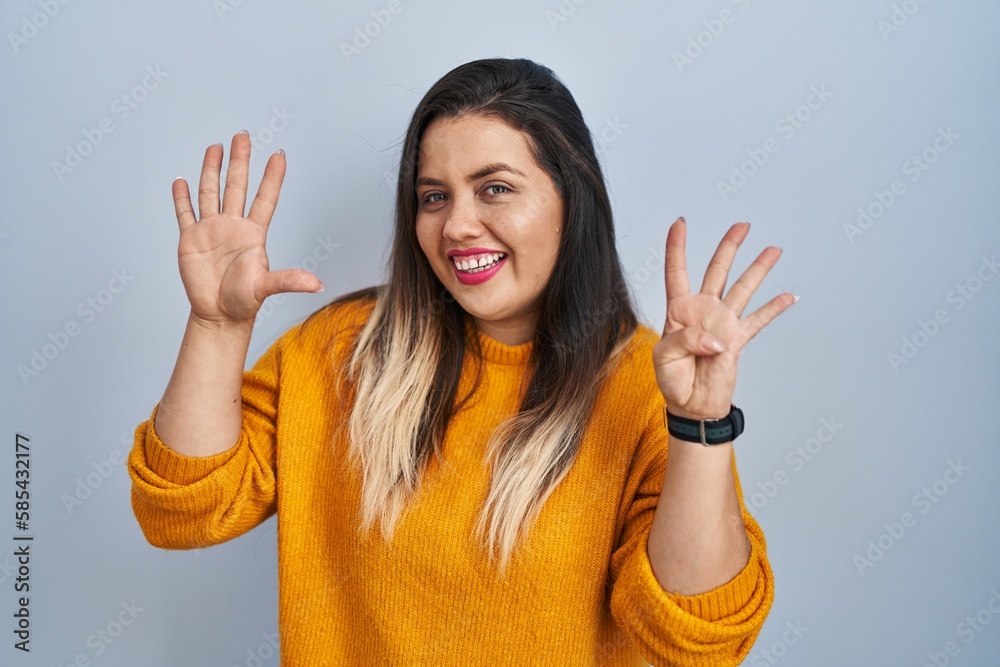 Young hispanic woman standing over isolated background showing and pointing up with fingers number nine while smiling confident and happy. Young hispanic woman standing over isolated background showing and pointing up with fingers number nine while smiling confident and happy.