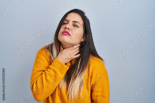 Young hispanic woman standing over isolated background touching painful neck, sore throat for flu, clod and infection © Krakenimages.com