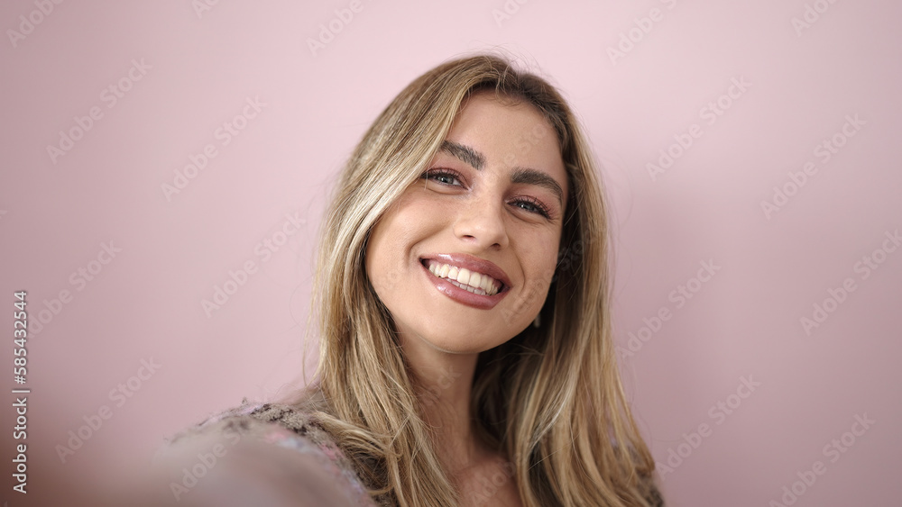 Young blonde woman smiling confident making selfie by camera over isolated pink background Young blonde woman smiling confident making selfie by camera over isolated pink background