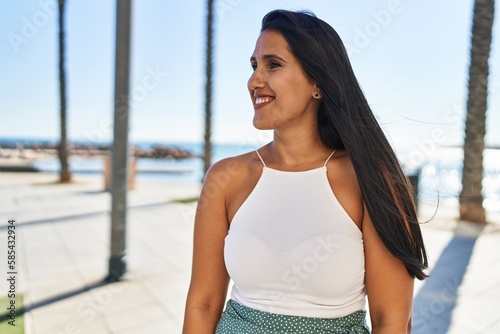 Young hispanic woman smiling confident walking at seaside