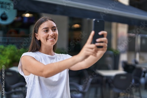 Young beautiful hispanic woman smiling confident making selfie by the smartphone at coffee shop terrace