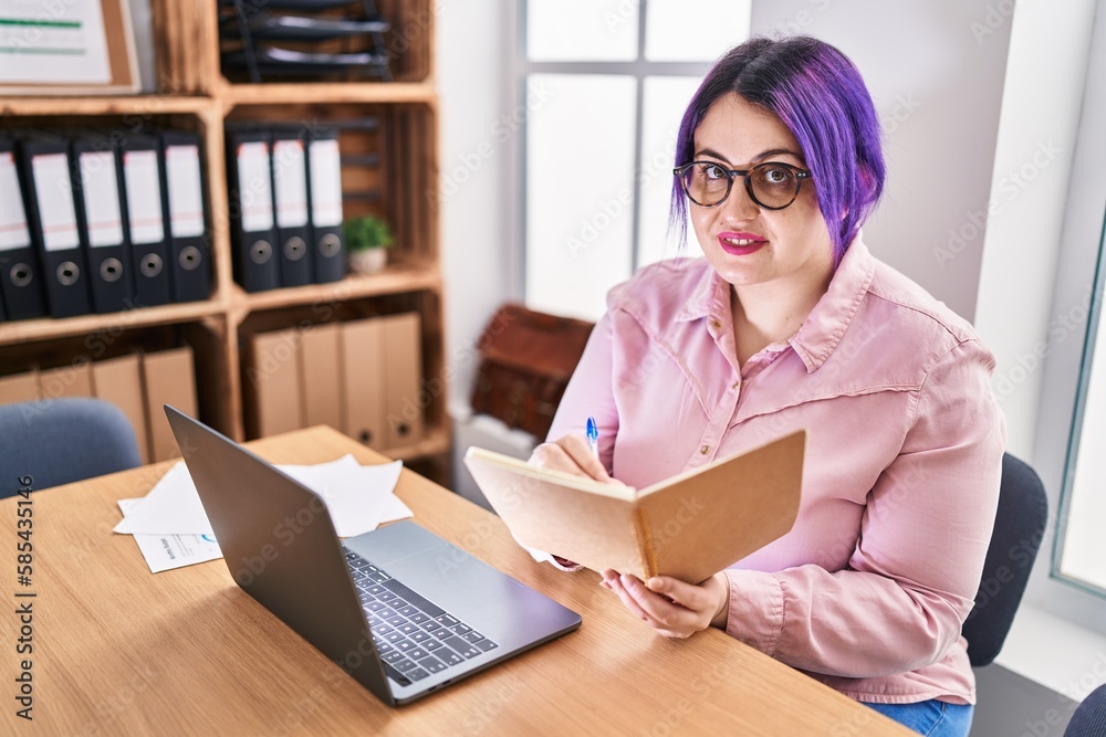 Young beautiful plus size woman business worker using laptop writing on notebook at office Young beautiful plus size woman business worker using laptop writing on notebook at office