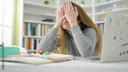 Young caucasian woman student stressed covering face with hands at library university