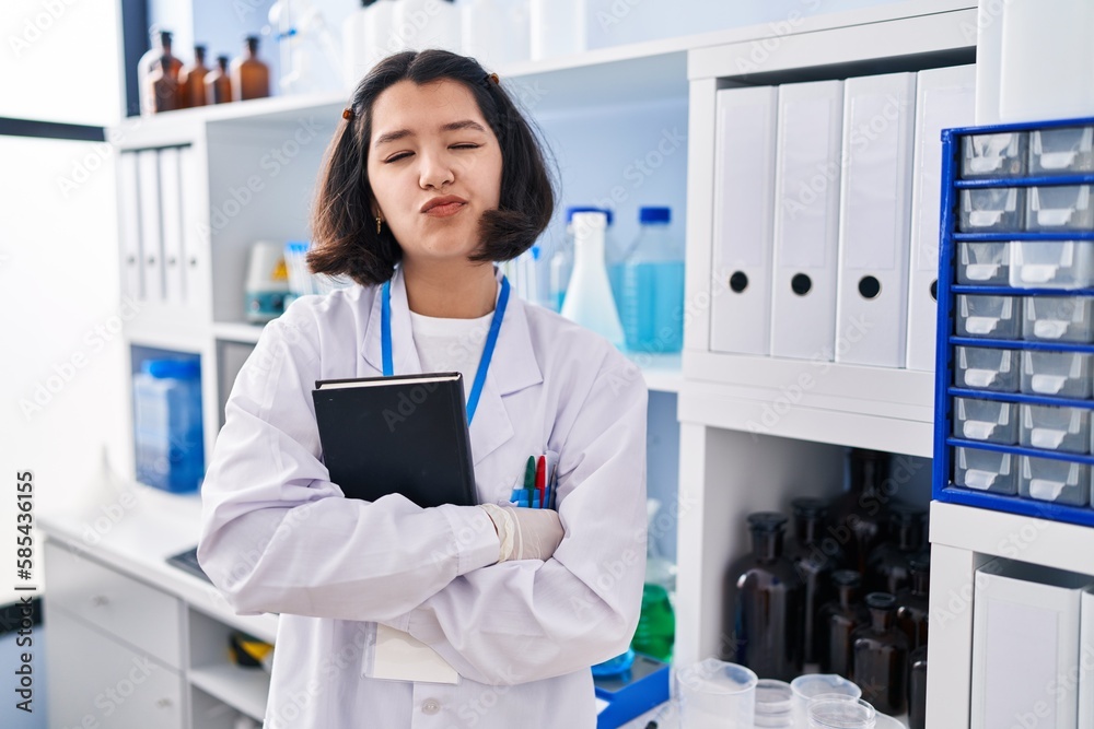 Young hispanic woman working at scientist laboratory looking at the camera blowing a kiss being lovely and sexy. love expression. Young hispanic woman working at scientist laboratory looking at the camera blowing a kiss being lovely and sexy. love expression.