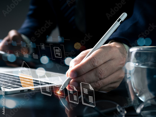 Document management, electronic signatures, and the idea of a paperless office. A businessman signs an electronic document with a stylus on a tablet computer and virtual notepad on a virtual screen. photo