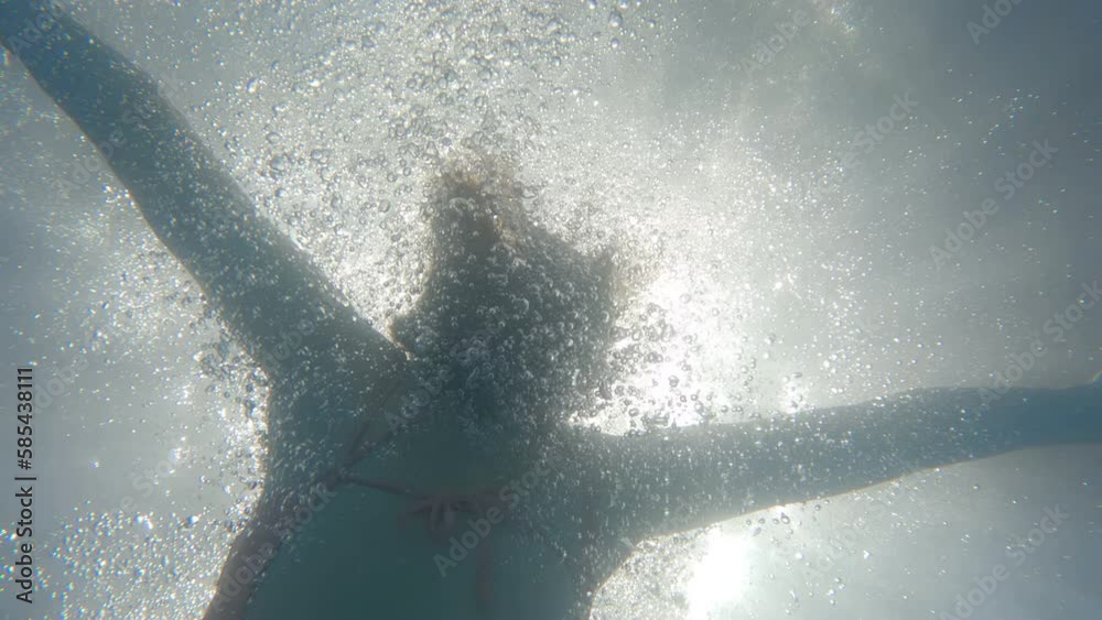 A girl in a swimsuit and pose bomb jumps into a water. The woman dives ...