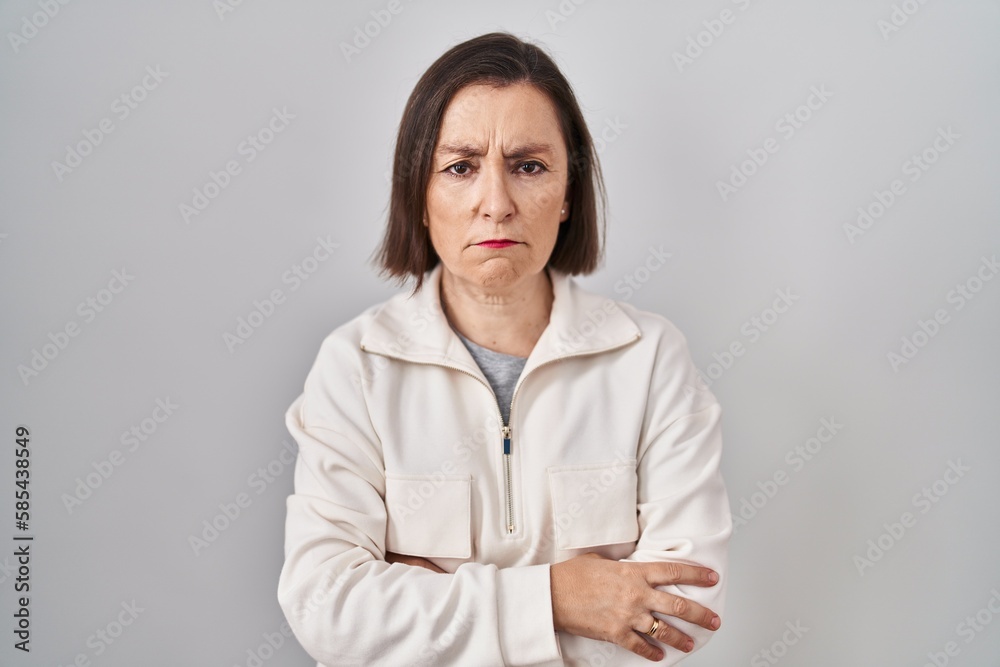 Middle age hispanic woman standing over isolated background skeptic and nervous, disapproving expression on face with crossed arms. negative person. Middle age hispanic woman standing over isolated background skeptic and nervous, disapproving expression on face with crossed arms. negative person.