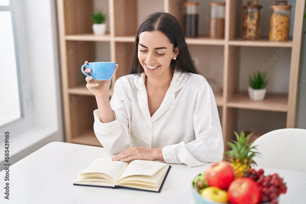 Young hispanic woman reading book drinking coffee at home Young hispanic woman reading book drinking coffee at home