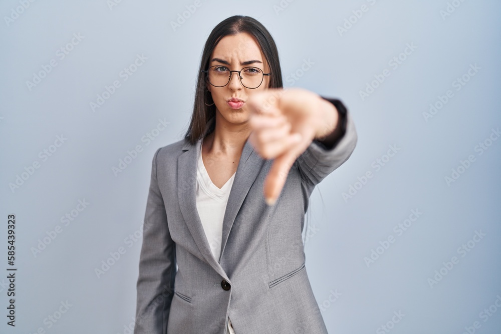 Hispanic business woman wearing glasses looking unhappy and angry showing rejection and negative with thumbs down gesture. bad expression. Hispanic business woman wearing glasses looking unhappy and angry showing rejection and negative with thumbs down gesture. bad expression.