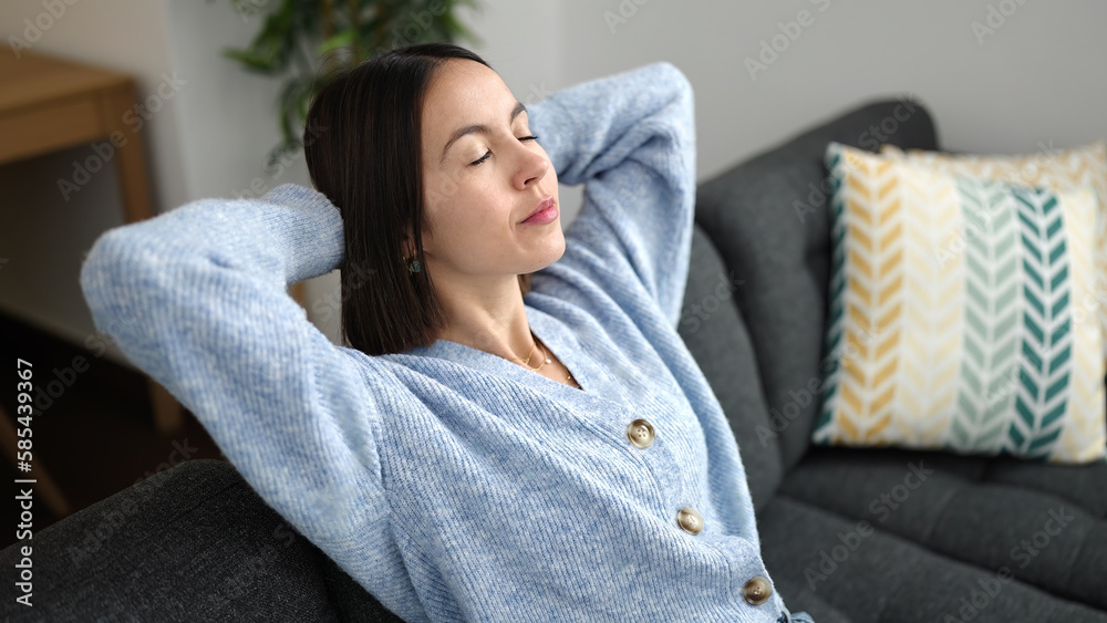 Young beautiful hispanic woman relaxed with hands on head sitting on sofa at home Young beautiful hispanic woman relaxed with hands on head sitting on sofa at home