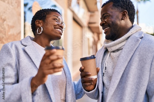 Man and woman couple standing together drinking coffee at street