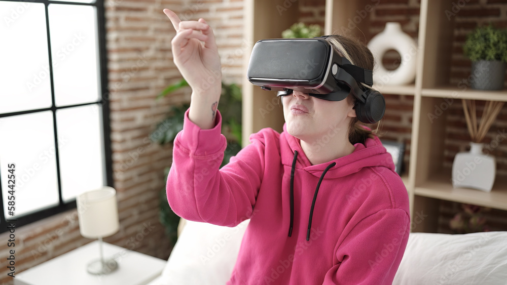 Young blonde woman playing video game using virtual reality glasses at bedroom Young blonde woman playing video game using virtual reality glasses at bedroom