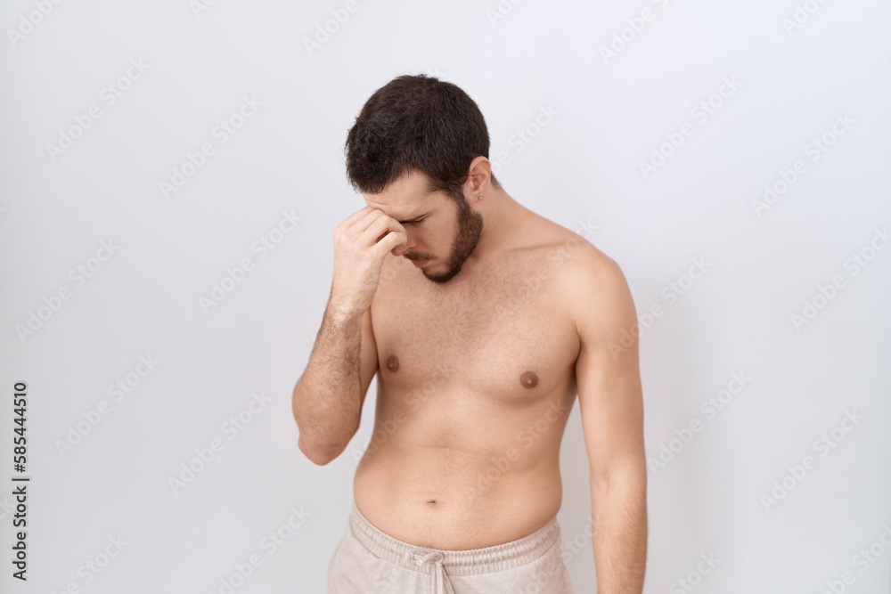 Young hispanic man standing shirtless over white background tired rubbing nose and eyes feeling fatigue and headache. stress and frustration concept.