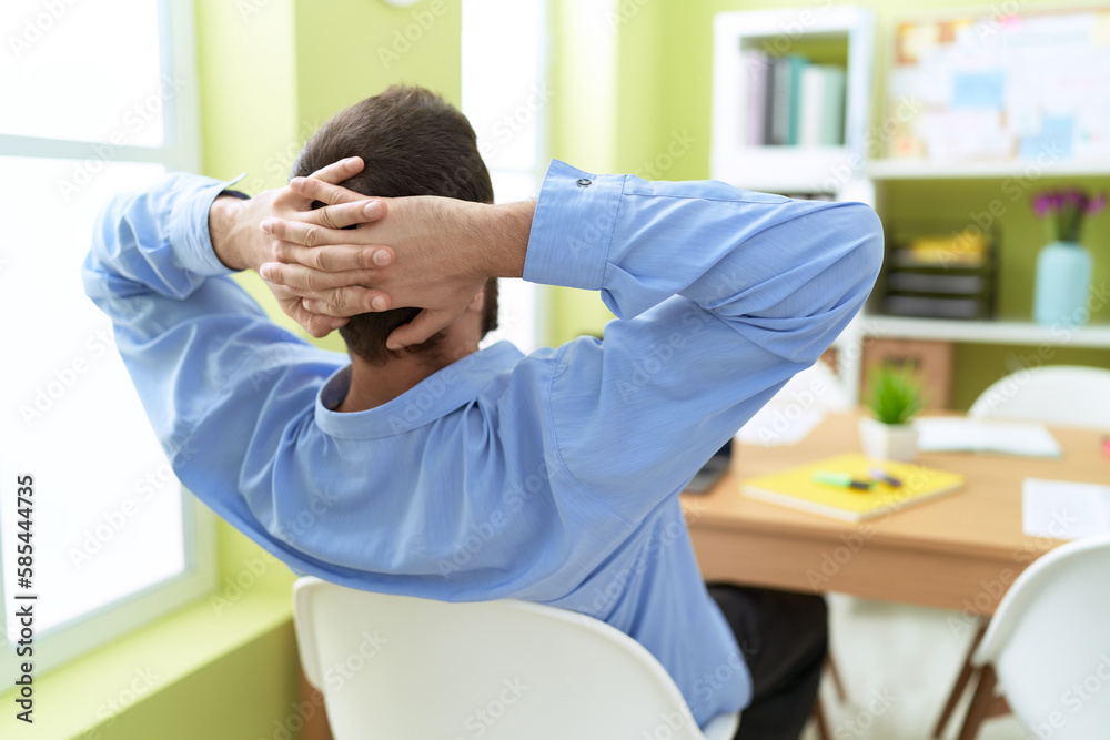 Young hispanic man business worker relaxed with hands on head at office