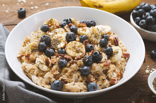 Oatmeal Bowl, Oat Porridge with Blueberry, Banana and Pecans in a Bowl on Wooden Background, Healthy Snack or Breakfast