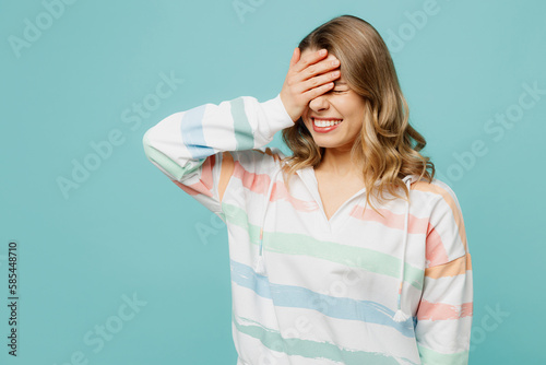 Young sad disappointed caucasian blonde woman wear hoody put hand on face facepalm epic fail mistaken omg gesture isolated on plain pastel light blue cyan background studio portrait Lifestyle concept