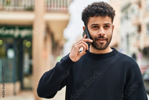 Young arab man smiling confident talking on the smartphone at street