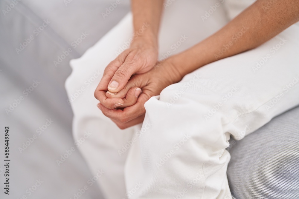 Middle age grey-haired woman sitting on sofa with hands together at home Middle age grey-haired woman sitting on sofa with hands together at home