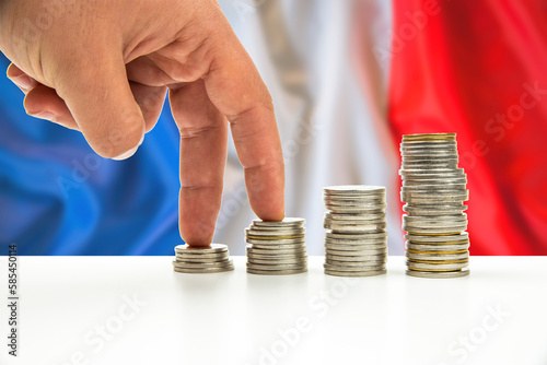 banknotes and coins in front of the national flag of France stack of silver and gold coin and hand gestures are walking for business concept. photo