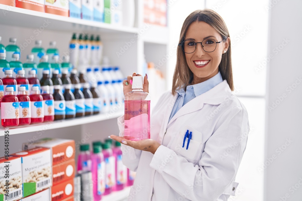 Young beautiful hispanic woman pharmacist smiling confident holding gel bottle at pharmacy