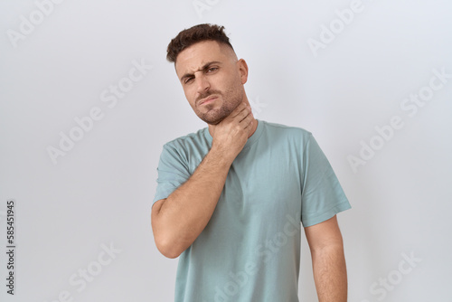 Hispanic man with beard standing over white background touching painful neck, sore throat for flu, clod and infection