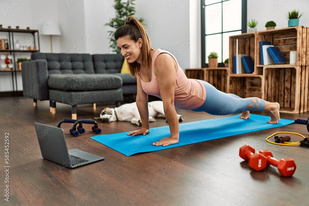 Obraz premium Young woman smiling confident having online abs exercise class at home