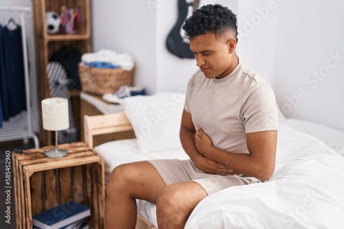Young latin man suffering for stomach flu at bedroom