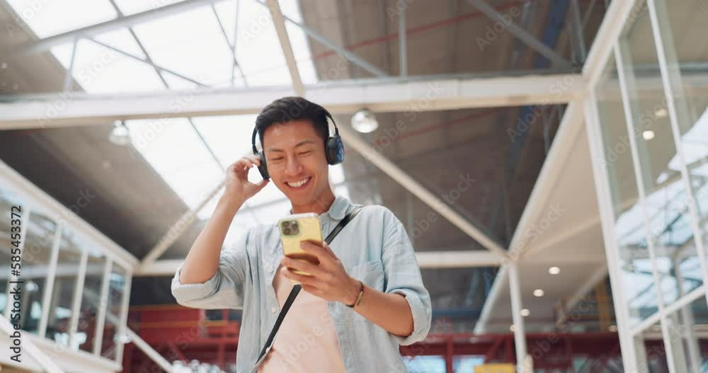 Asian man, phone and headphones for listening to music and dancing while walking in creative office with smile, happiness and positive mindset. Male entrepreneur during travel with network connection