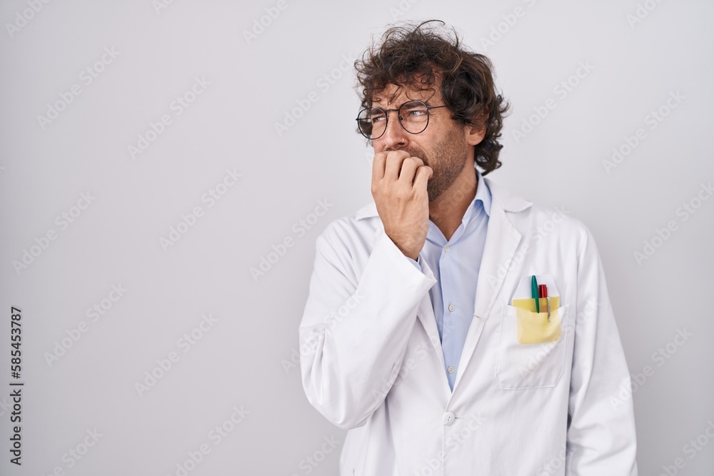 Hispanic young man wearing doctor uniform looking stressed and nervous with hands on mouth biting nails. anxiety problem. Hispanic young man wearing doctor uniform looking stressed and nervous with hands on mouth biting nails. anxiety problem.