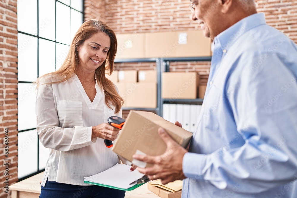 Middle age man and woman ecommerce business workers scanning label using barcode reader at office Middle age man and woman ecommerce business workers scanning label using barcode reader at office