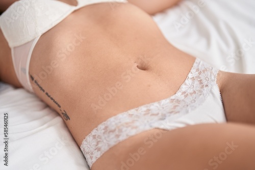 Young woman wearing lingerie lying on bed at bedroom