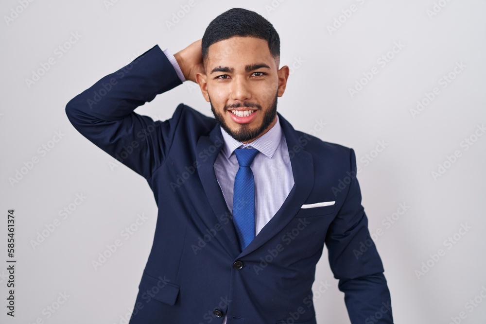 Young hispanic man wearing business suit and tie smiling confident touching hair with hand up gesture, posing attractive and fashionable Young hispanic man wearing business suit and tie smiling confident touching hair with hand up gesture, posing attractive and fashionable