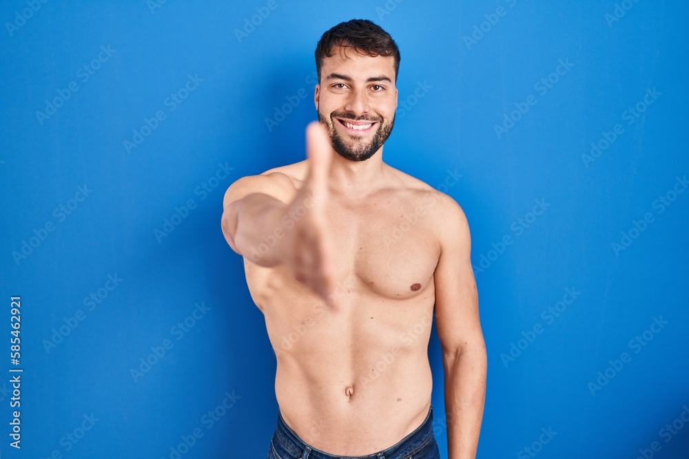 Obraz premium Handsome hispanic man standing shirtless smiling friendly offering handshake as greeting and welcoming. successful business.