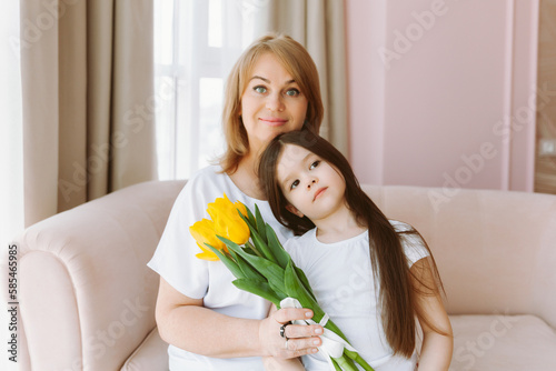 A little granddaughter gives her grandmother a bouquet of tulips. A happy family. The concept of gratitude, love, well-being
