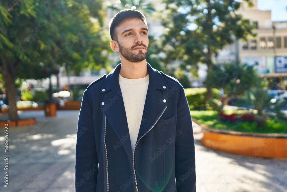 Young hispanic man looking to the side with serious expression at park