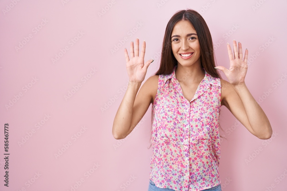 Young hispanic woman with long hair standing over pink background showing and pointing up with fingers number ten while smiling confident and happy. Young hispanic woman with long hair standing over pink background showing and pointing up with fingers number ten while smiling confident and happy.