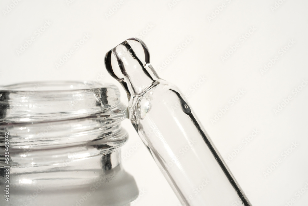 Glass pipette with serum and frosted glass bottle on light background. Front view and close-up view. Glass pipette with serum and frosted glass bottle on light background. Front view and close-up view.